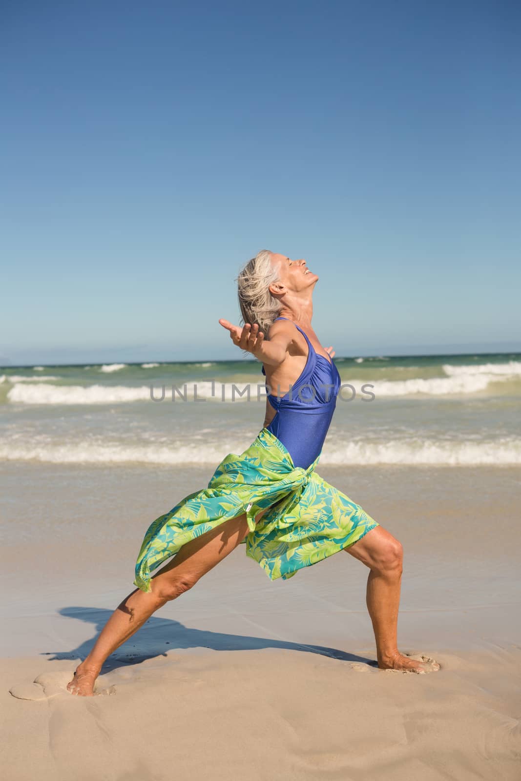 Side view of woman practising yoga while standing on shore at beach