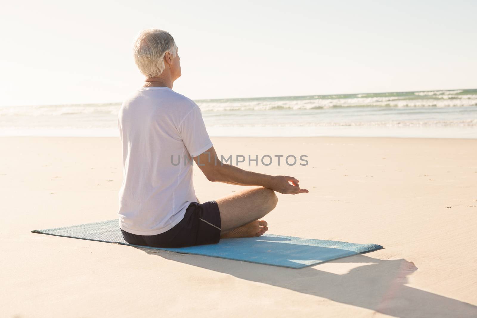 Senior man doing yoga at beach by Wavebreakmedia