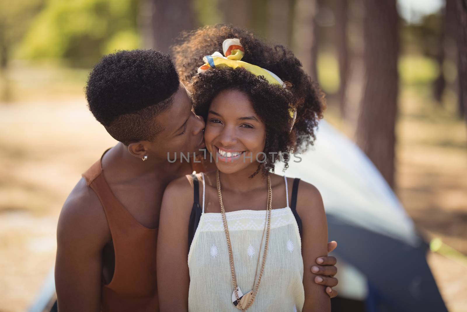 Close up of romantic couple sitting against tent on field