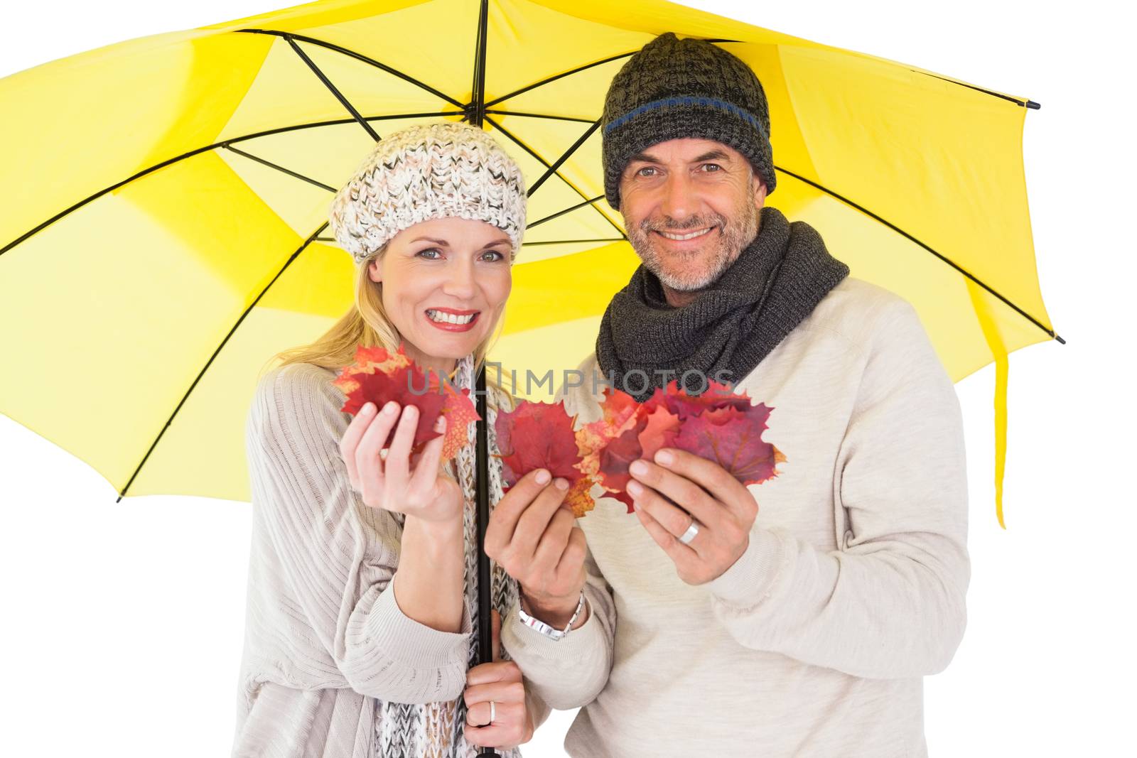 Couple in winter fashion showing autumn leaves under umbrella by Wavebreakmedia