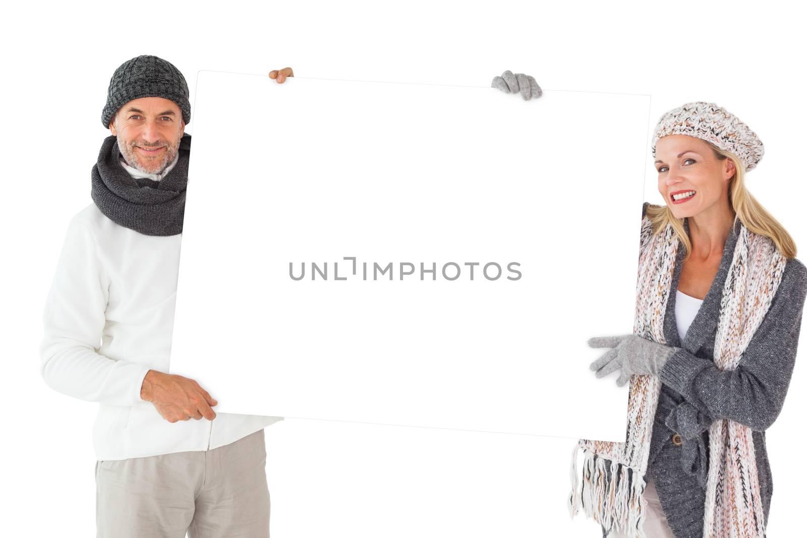 Smiling couple in winter fashion holding poster on white background
