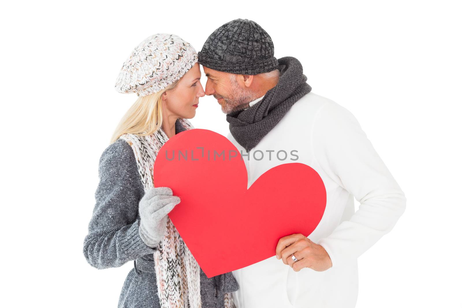 Smiling couple in winter fashion posing with heart shape on white background