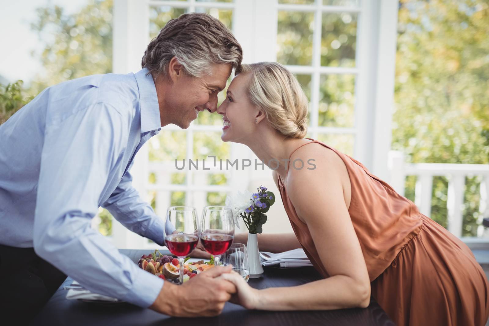 Romantic couple holding hands while having meal by Wavebreakmedia