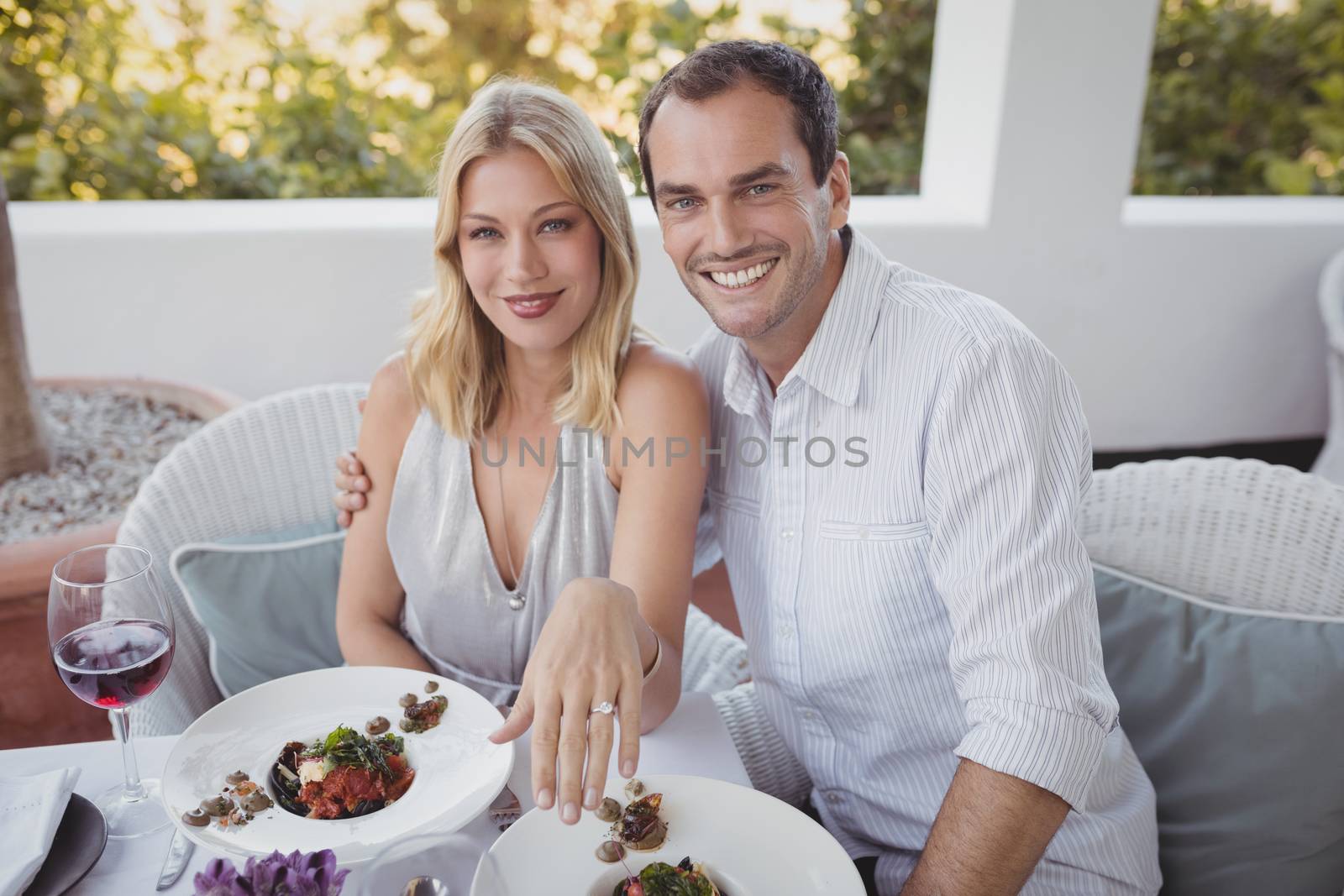 Portrait of romantic couple with their engagement ring in restaurant