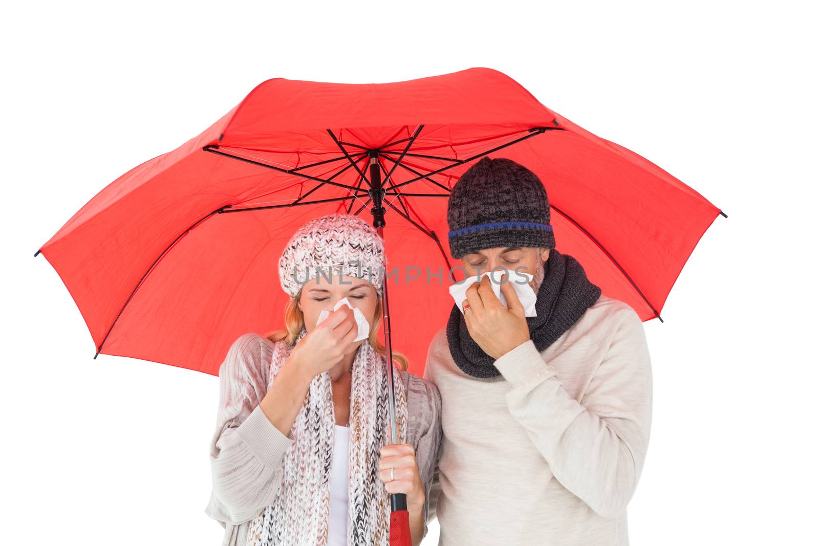 Couple in winter fashion sneezing under umbrella by Wavebreakmedia