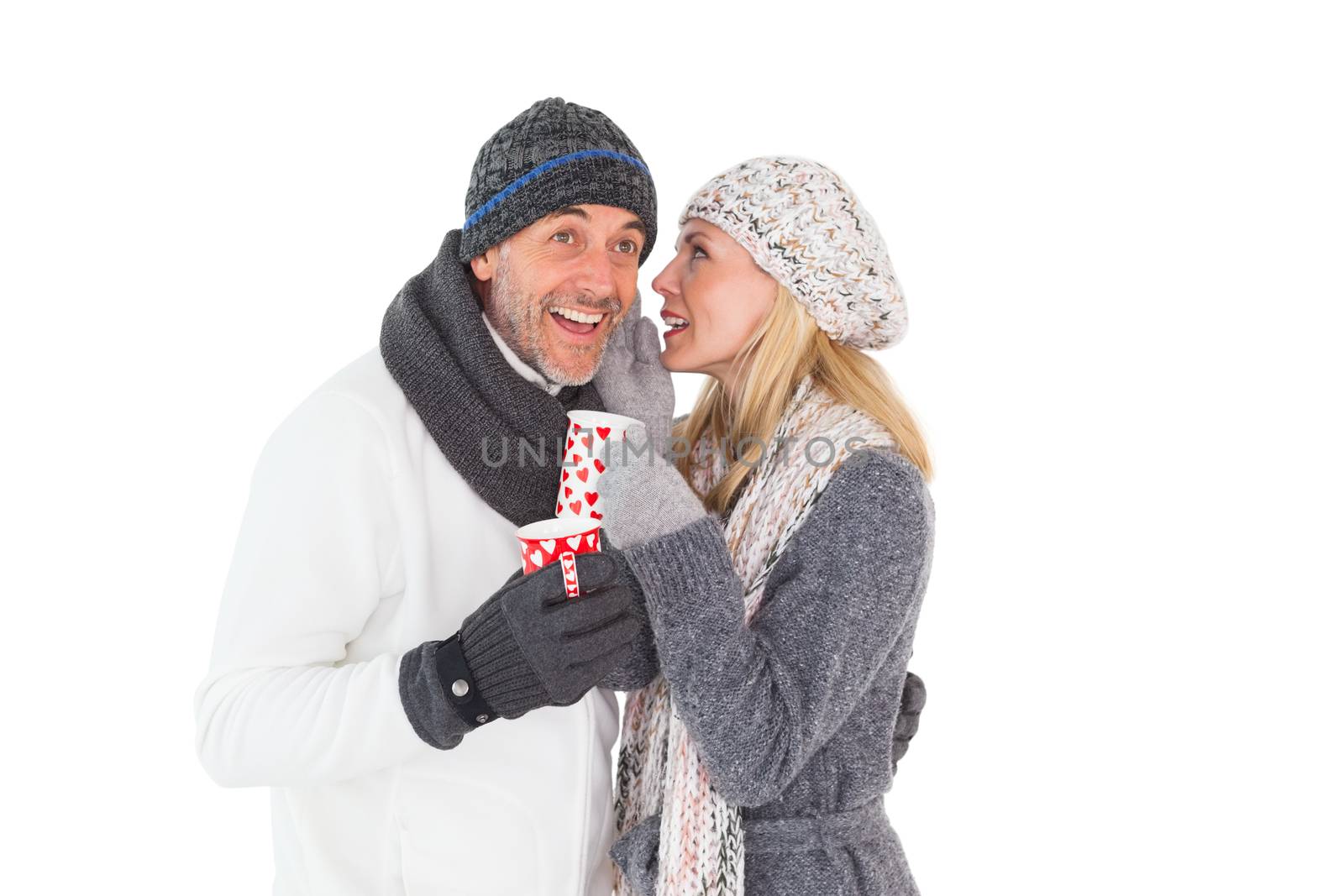 Happy couple in winter fashion holding mugs by Wavebreakmedia