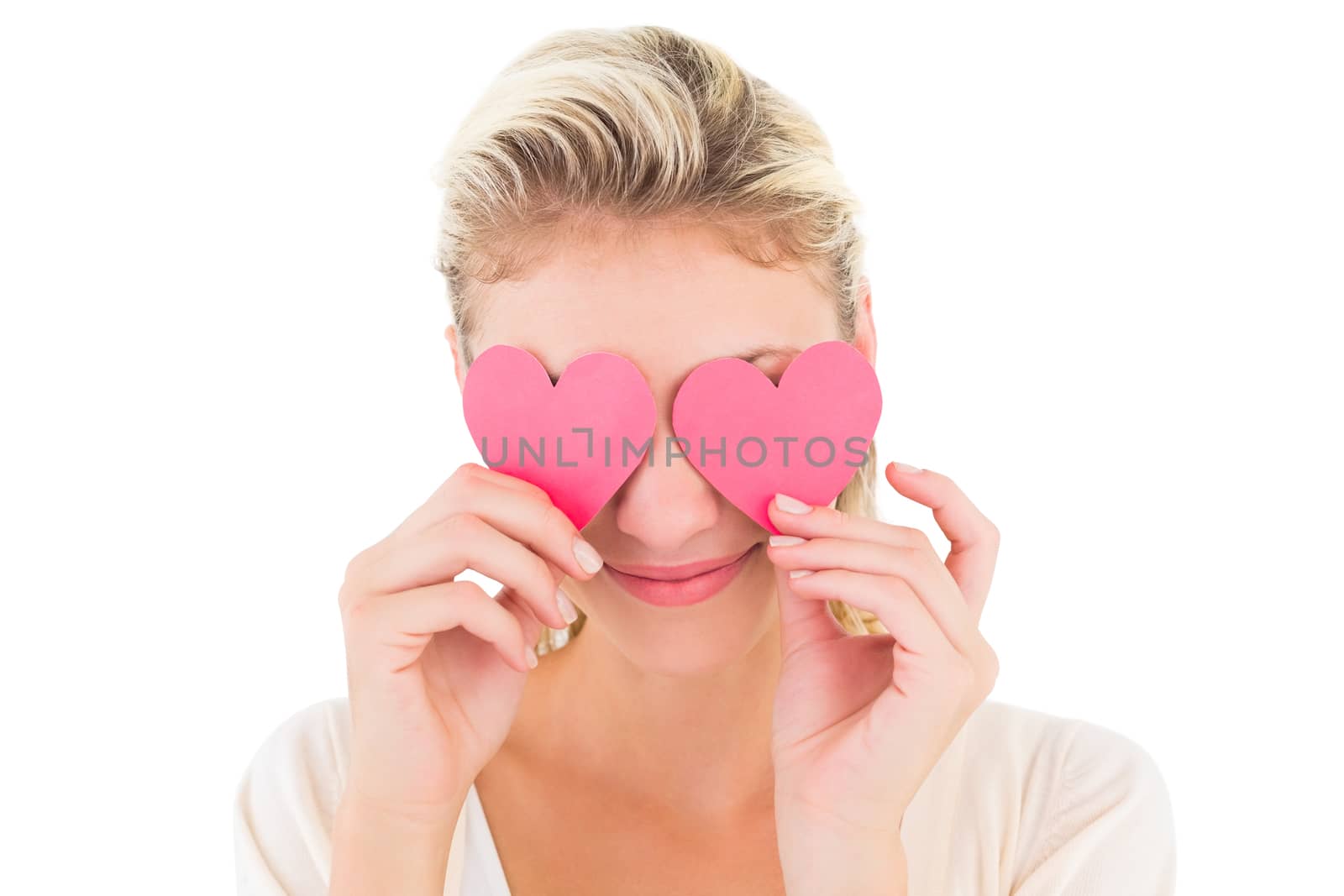 Attractive young blonde holding hearts over eyes on white background