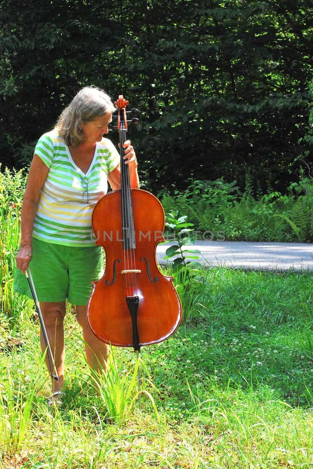 Mature female cellist with her instrument outside.
