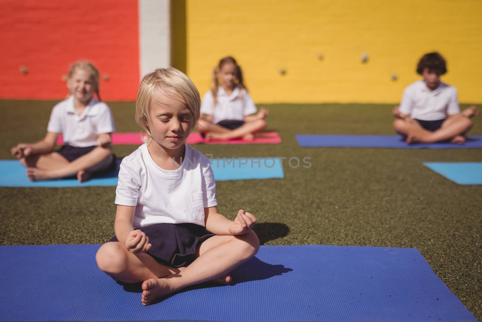Schoolkids practicing yoga in schoolyard