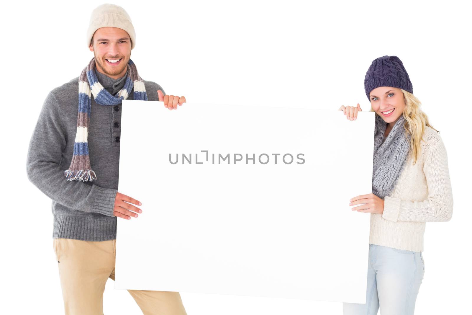 Attractive couple in winter fashion showing poster on white background