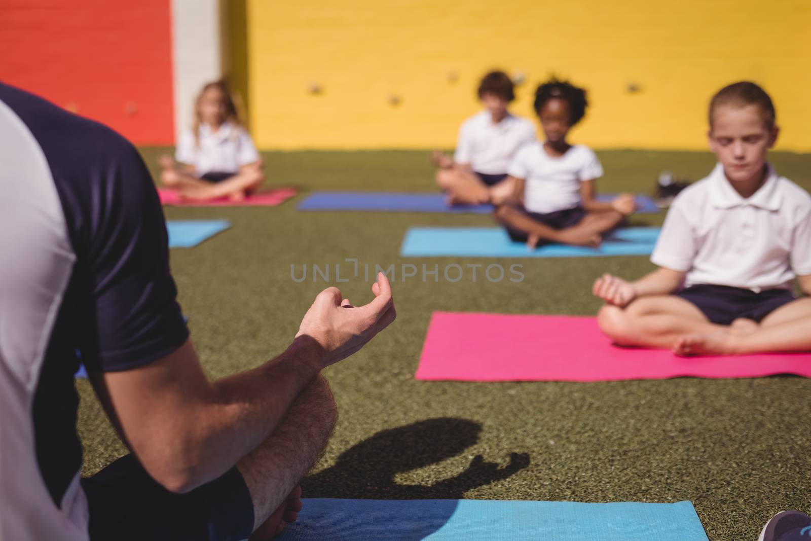 Coach and schoolkids practicing yoga by Wavebreakmedia