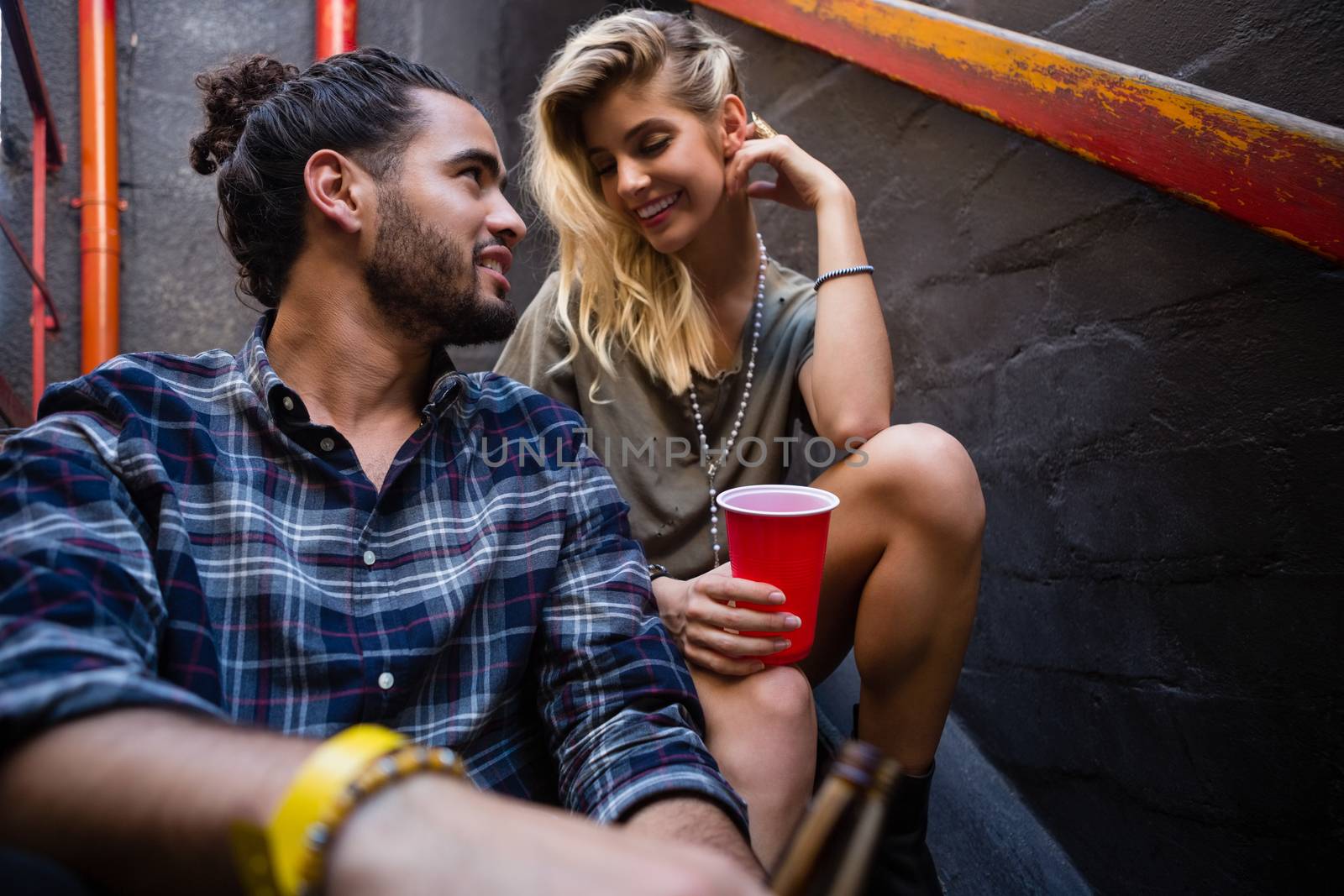 Romantic couple enjoying while having drink on staircase of bar