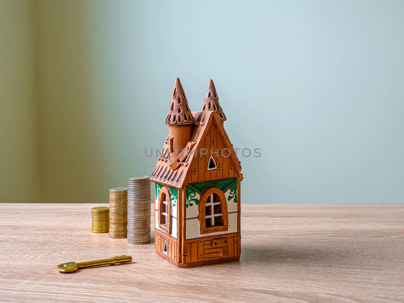 Model of a house, Stack of European Euro coins and golden key On Wooden Table. Real estate agency, mortgage loan, lottery, buying property.Home loan and investment concept. Copy space