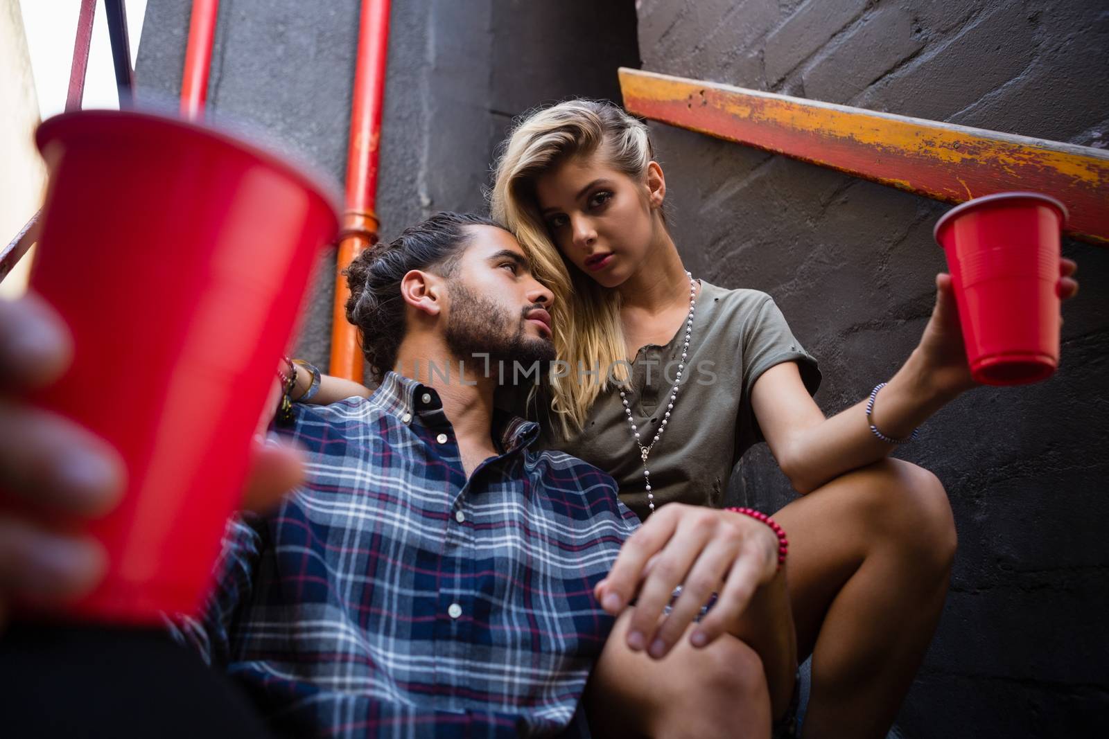 Romantic couple enjoying while having drink on staircase of bar