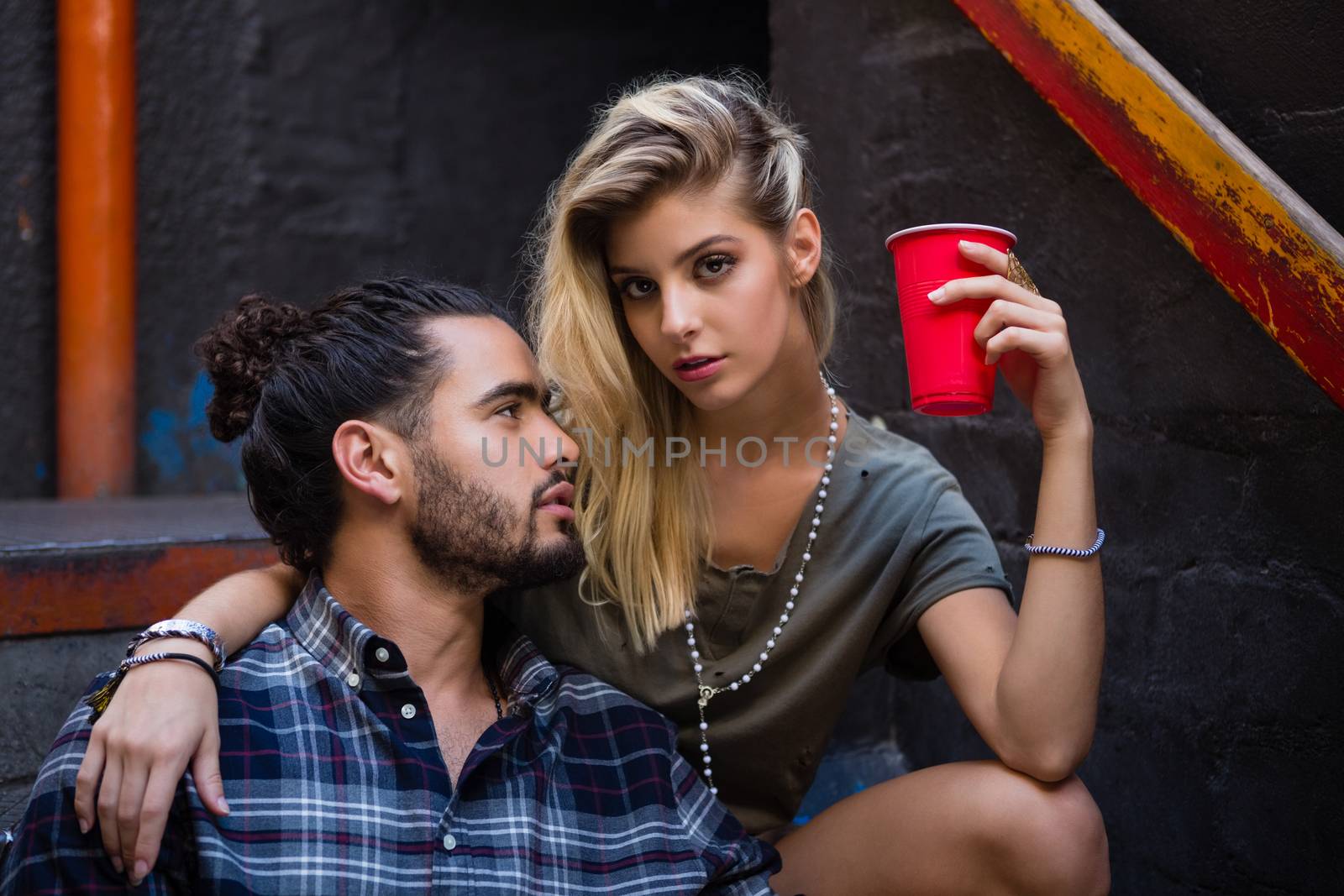 Romantic couple enjoying while having drink on staircase by Wavebreakmedia