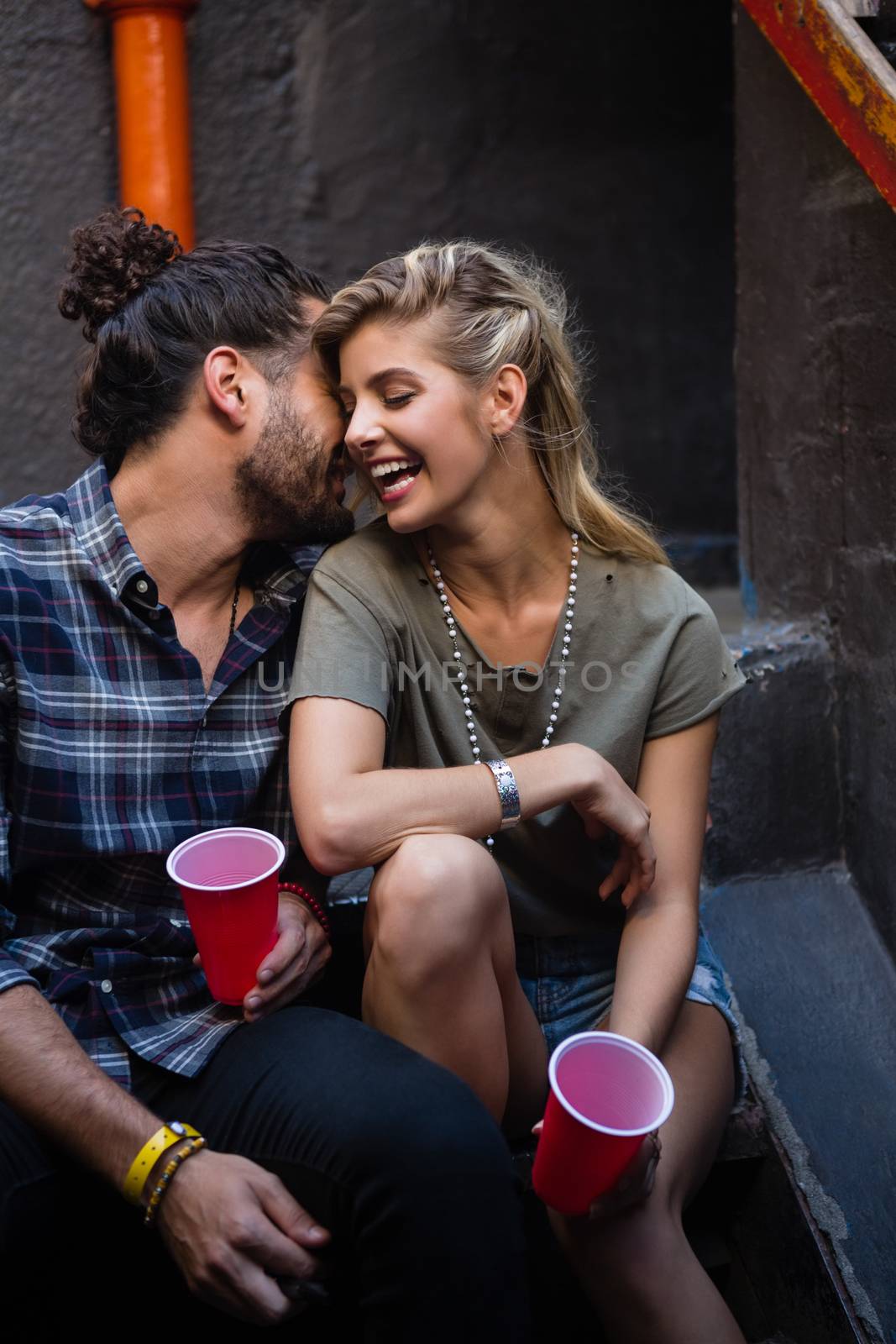 Romantic couple enjoying while having drink on staircase by Wavebreakmedia