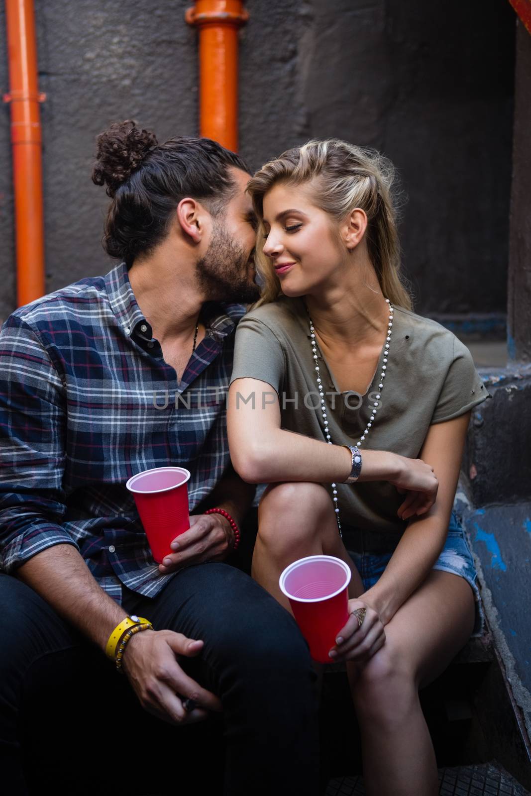 Romantic couple enjoying while having drink on staircase of bar