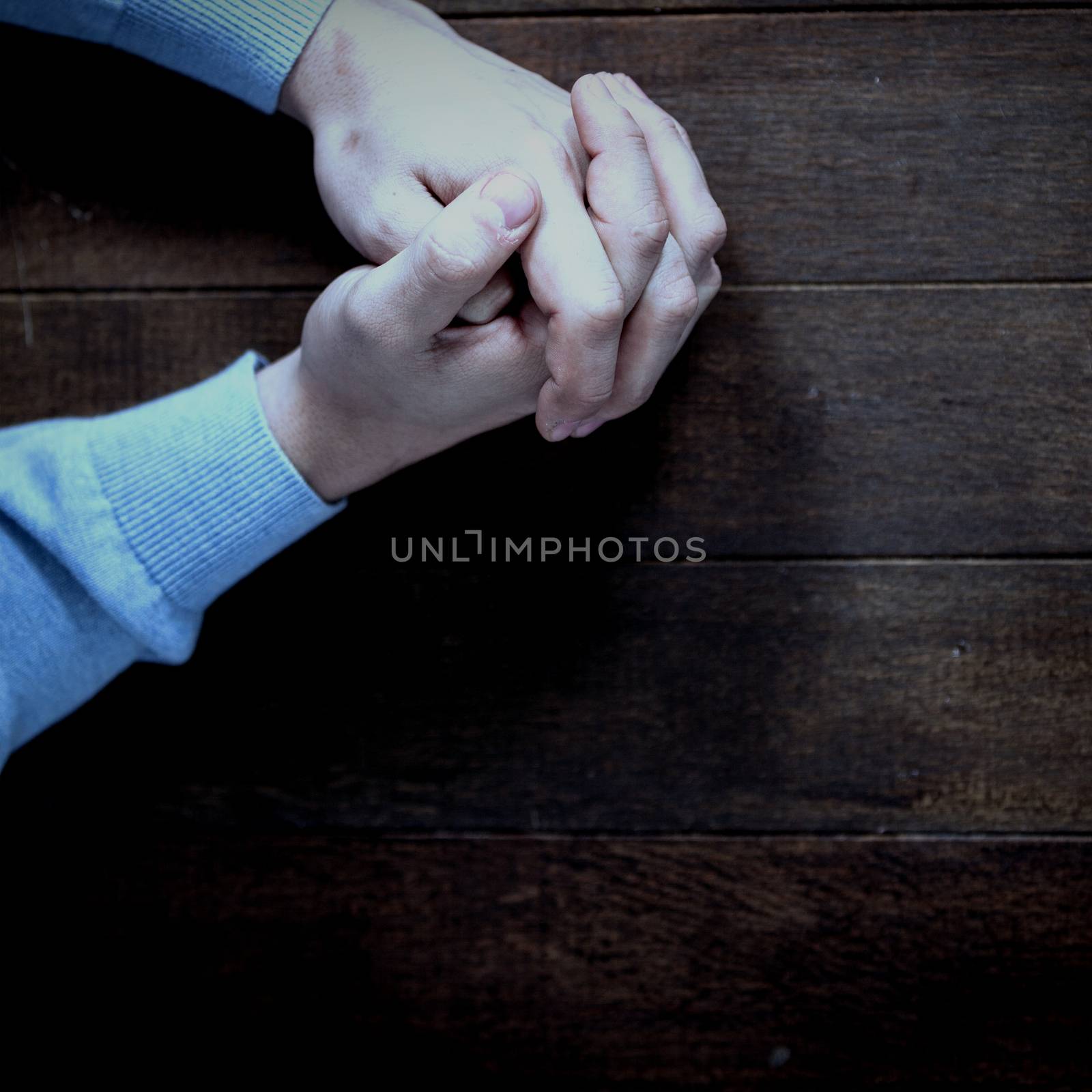 Man praying on wooden table by Wavebreakmedia