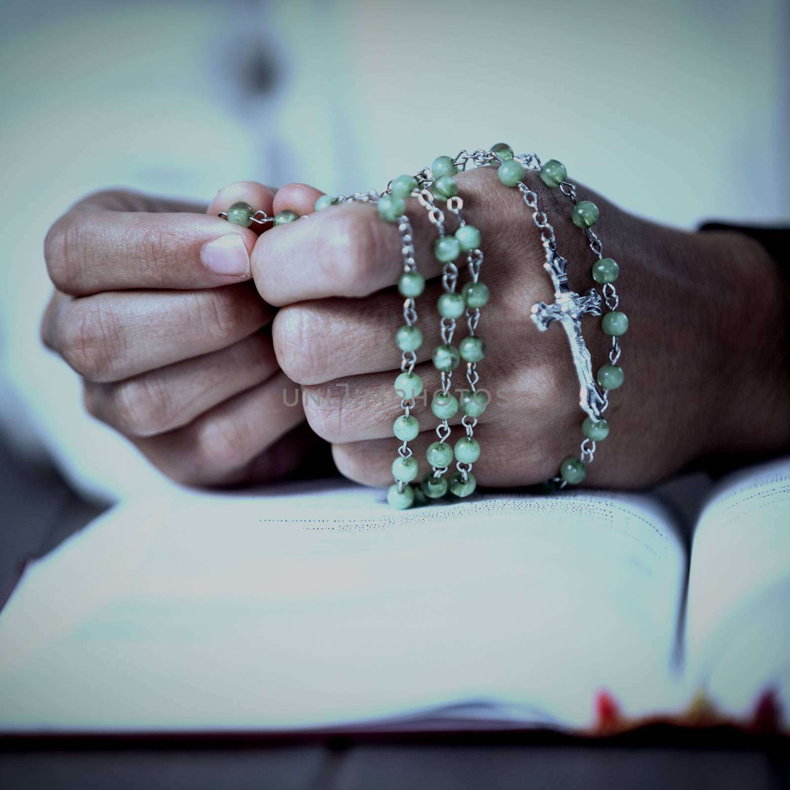 Praying hands of woman with rosary and bible by Wavebreakmedia