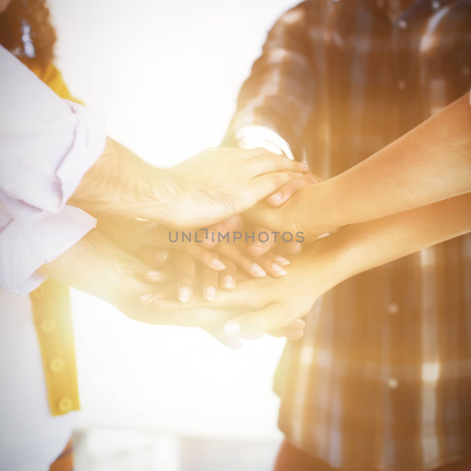 Creative business team stacking hands together in office