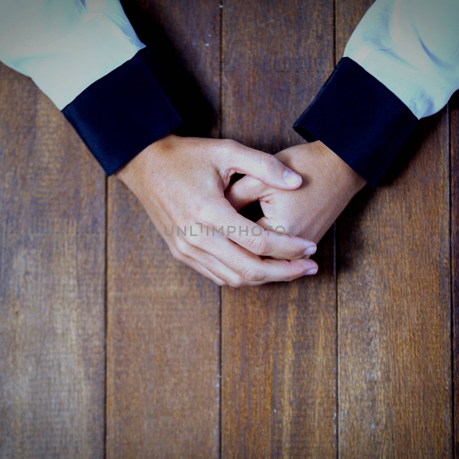 Praying hands of woman on wooden desk