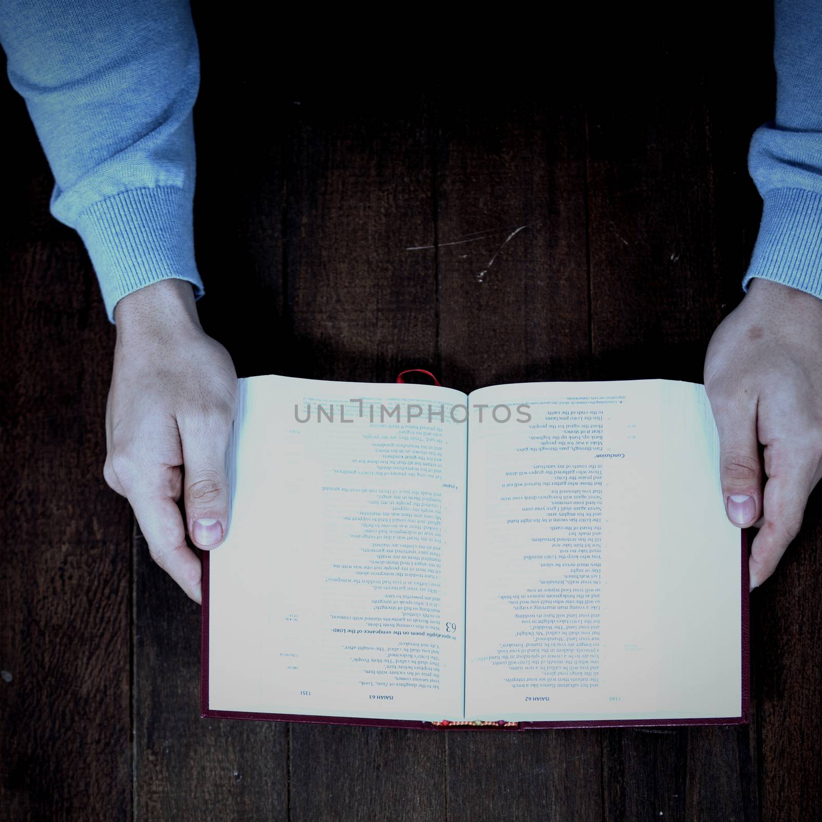 Cropped man holding bible on wooden table