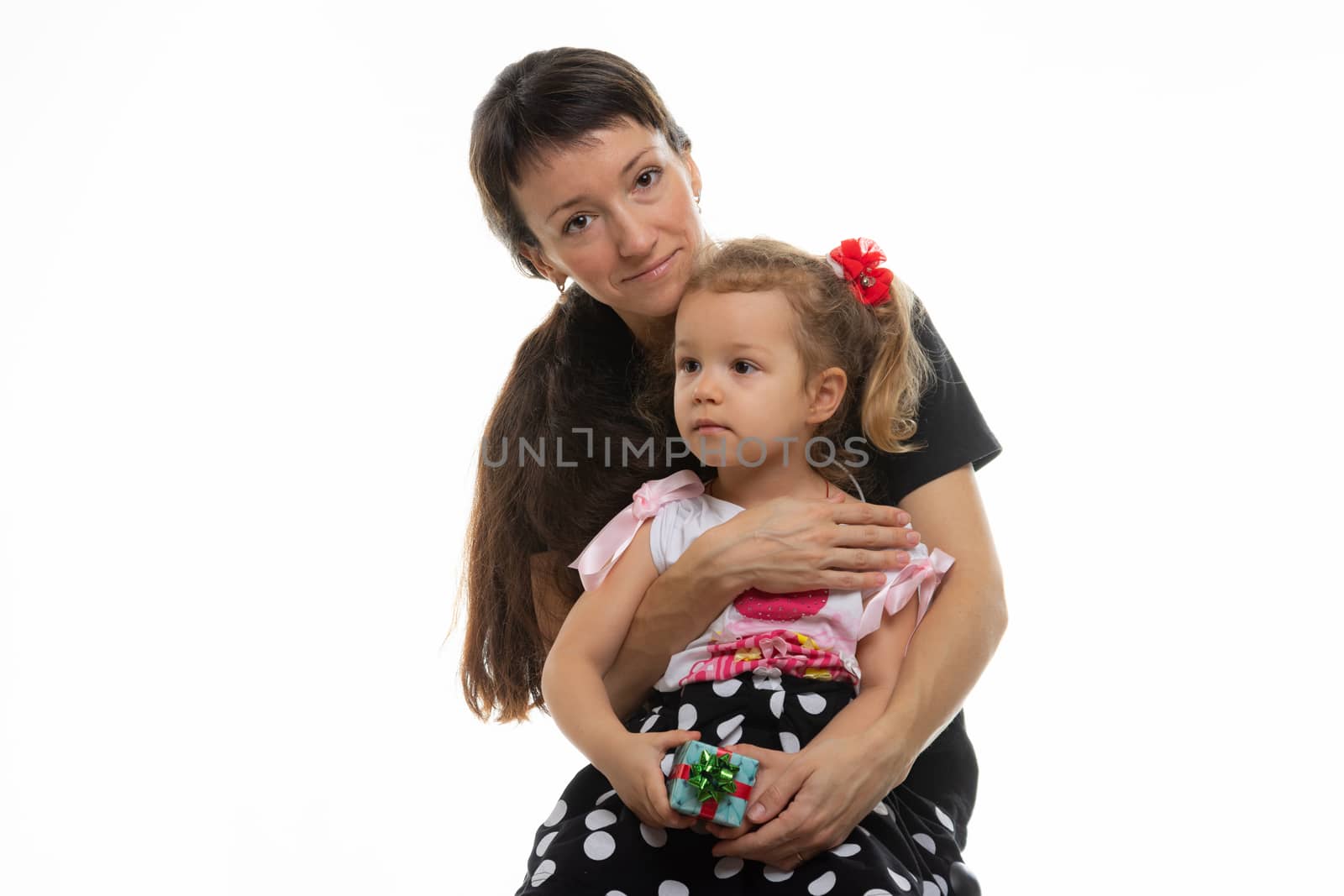 Four-year-old daughter sits on mother's lap, white background