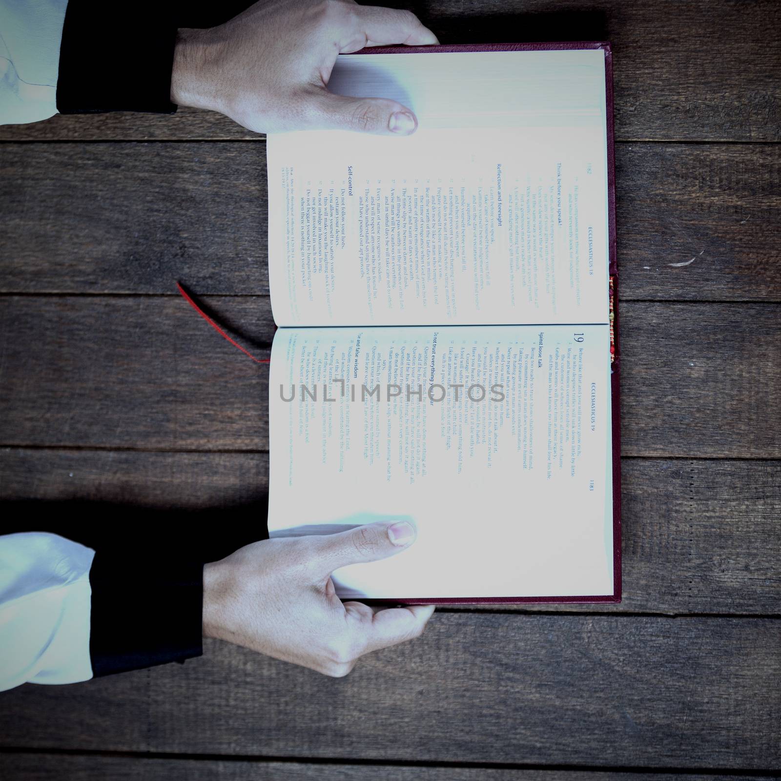 Cropped woman holding bible on wooden table