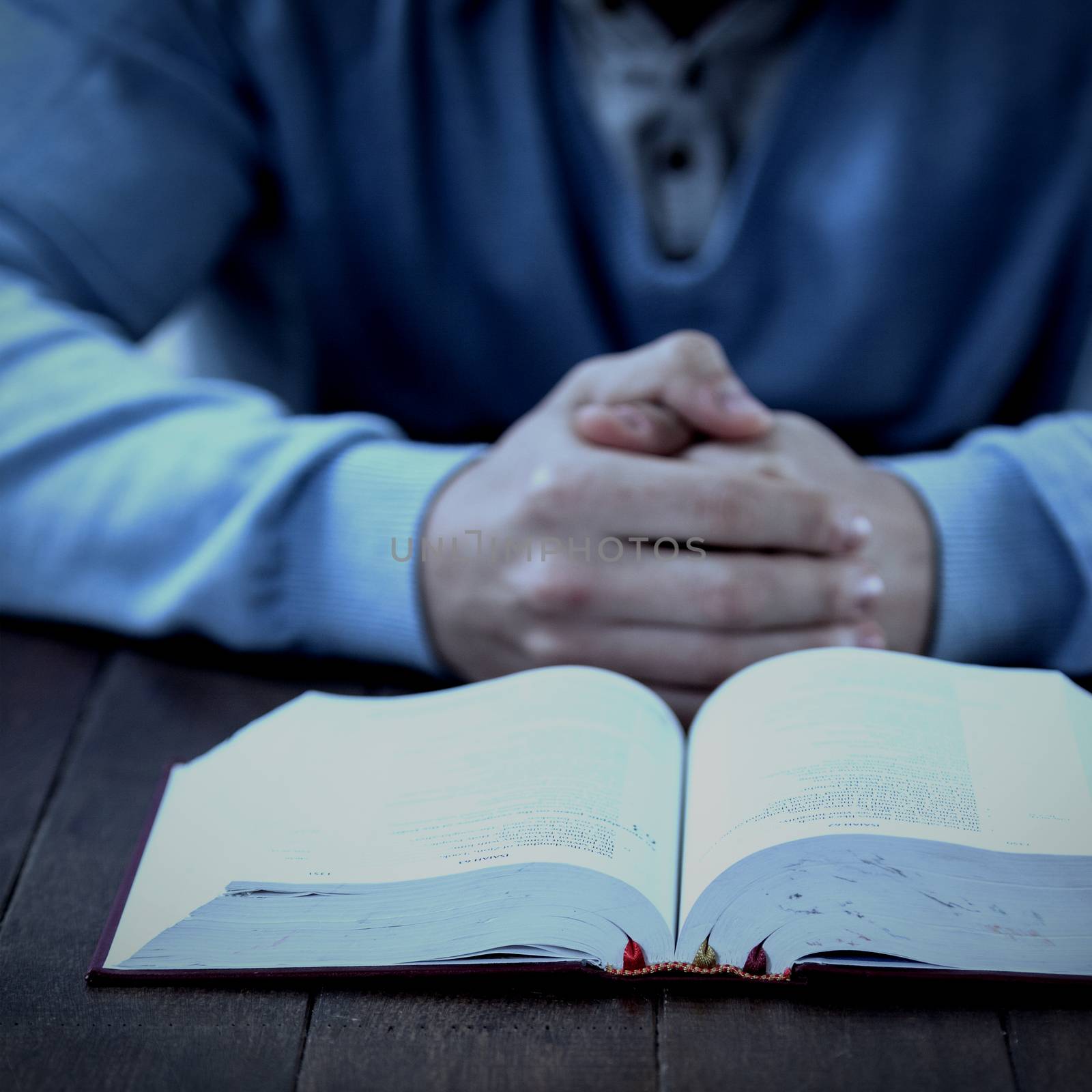 Man with bible praying at table by Wavebreakmedia