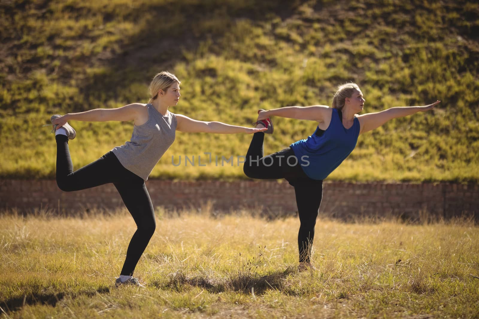 Beautiful women praising yoga during obstacle course in boot camp