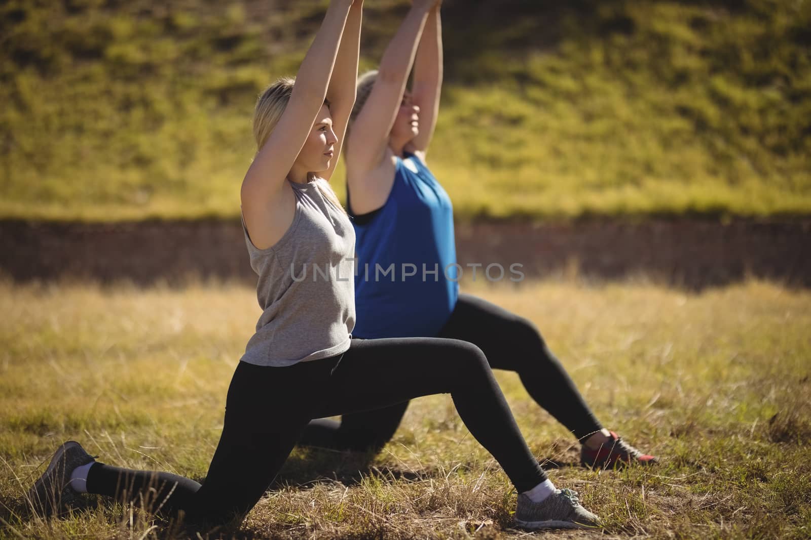 Beautiful women praising yoga during obstacle course in boot camp