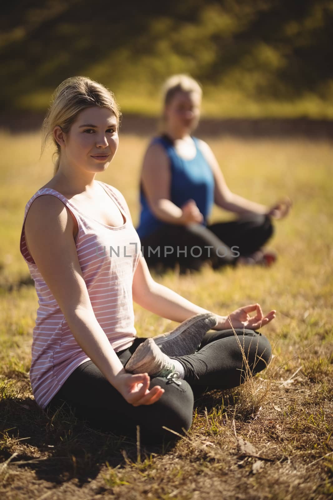 Women practicing yoga during obstacle course by Wavebreakmedia