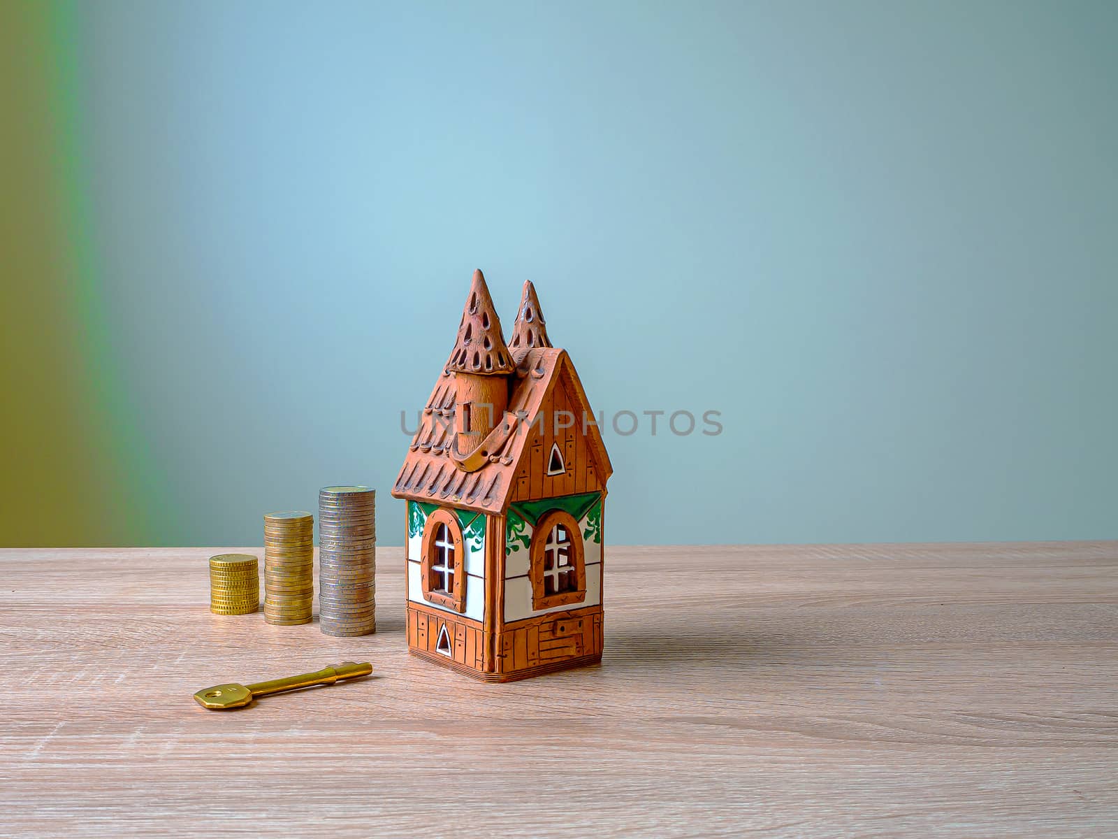 Model of a house, Stack of European Euro coins and golden key On Wooden Table. Real estate agency, mortgage loan, lottery, buying property.Home loan and investment concept. Copy space