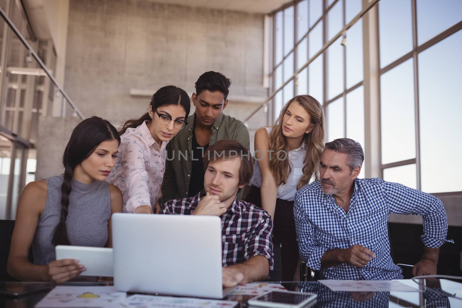 Business people discussing over laptop at creative office desk