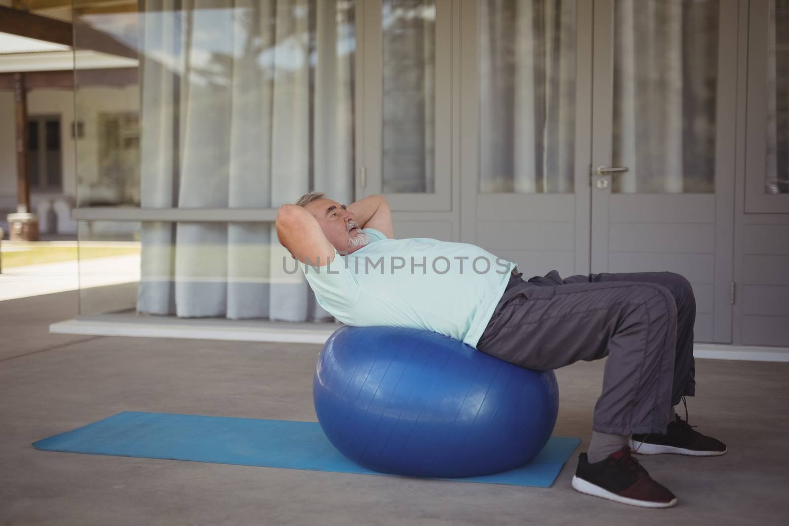 Senior man doing stretching exercise on exercise ball by Wavebreakmedia