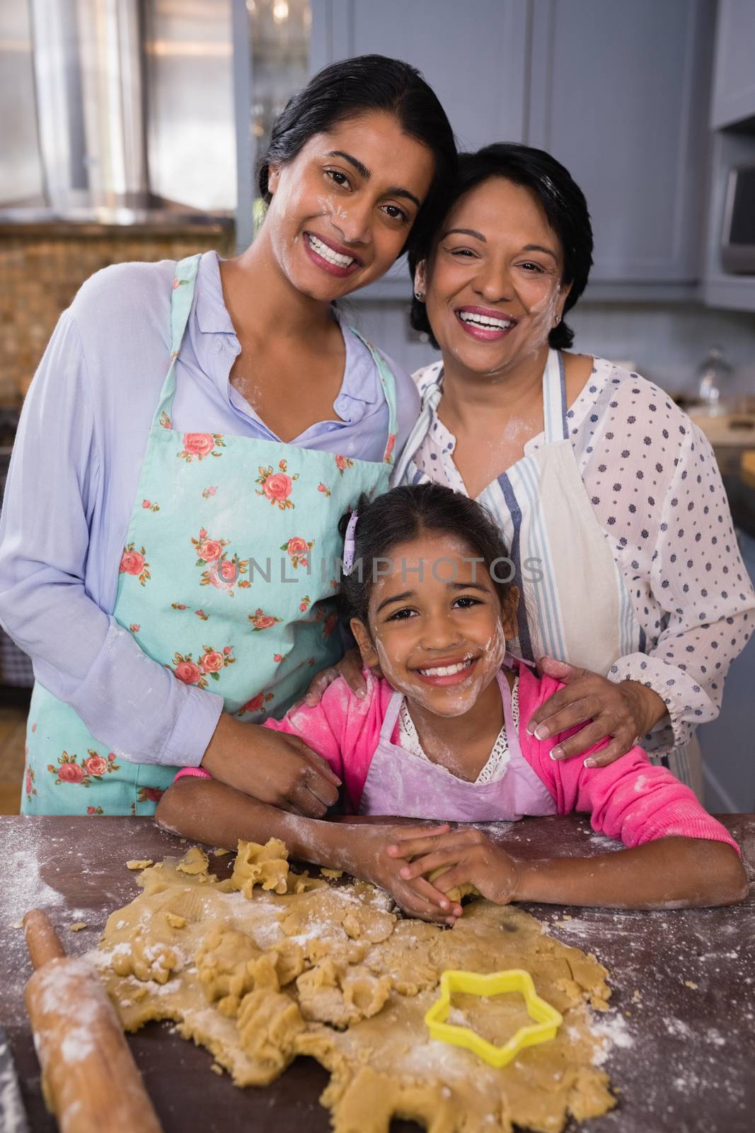 Portrait of smiling multi-generation family standing by dough in kitchen by Wavebreakmedia