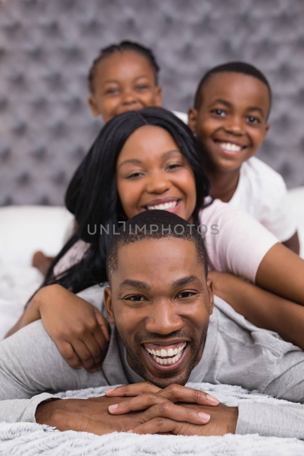 Portrait of smiling man with family lying on bed by Wavebreakmedia