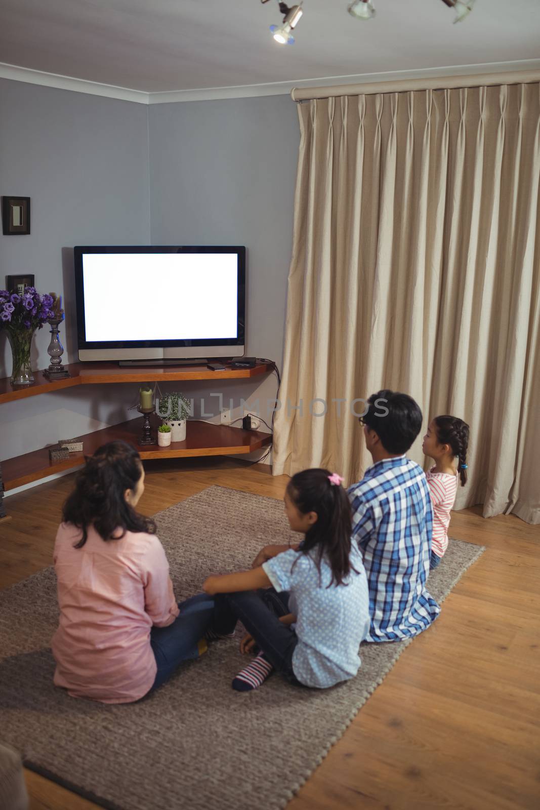 Family watching television together in living room at home