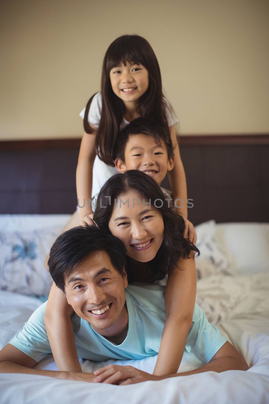 Portrait of happy family having fun on bed in the bed room at home