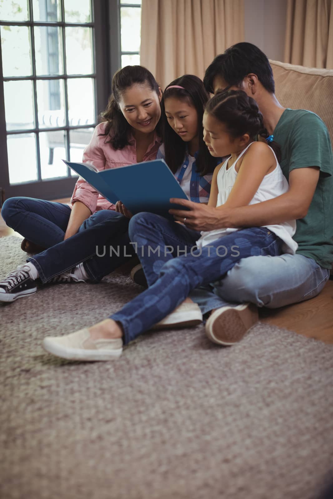 Family watching photo album together in living room at home