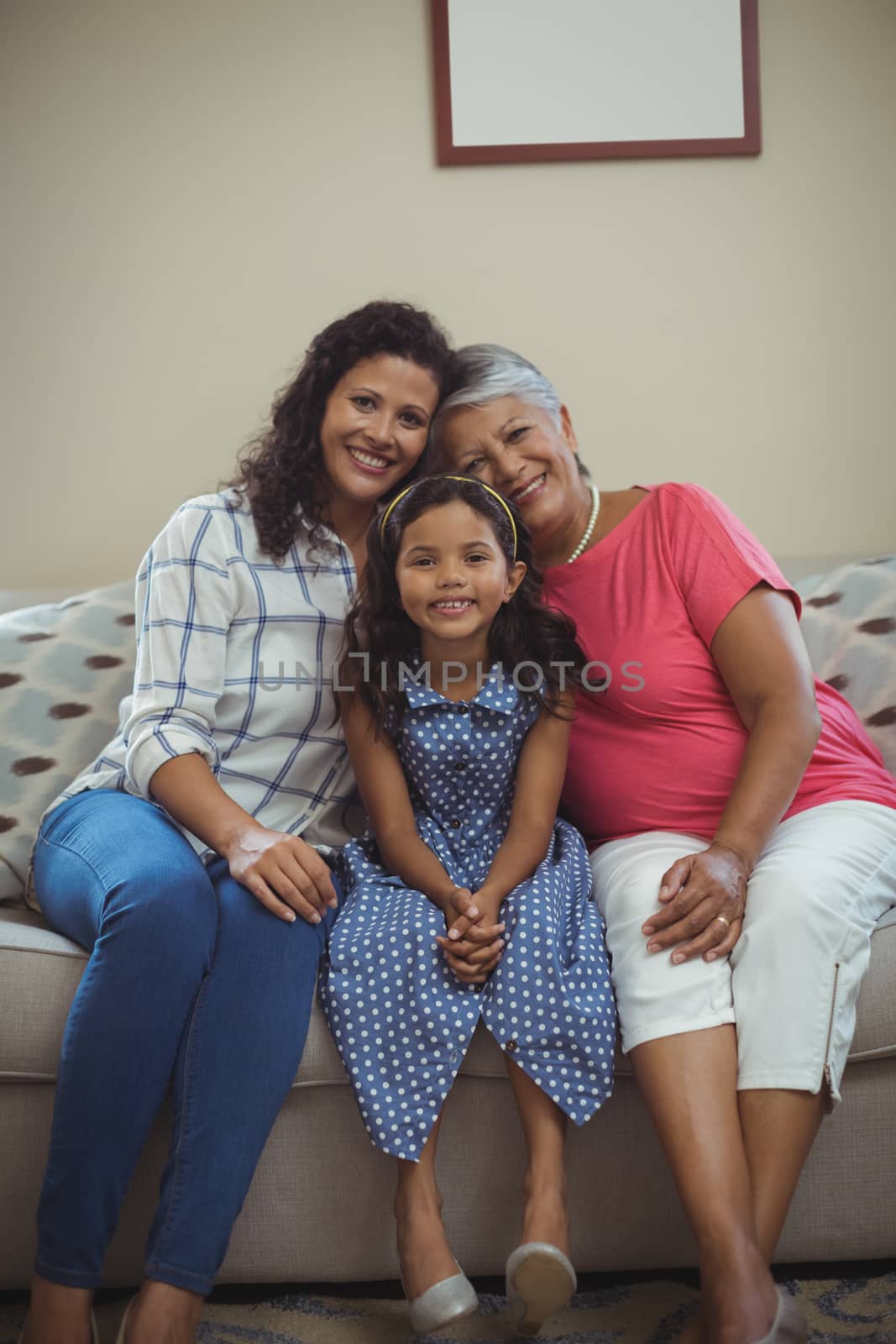Portrait of happy family sitting on sofa in living room at home