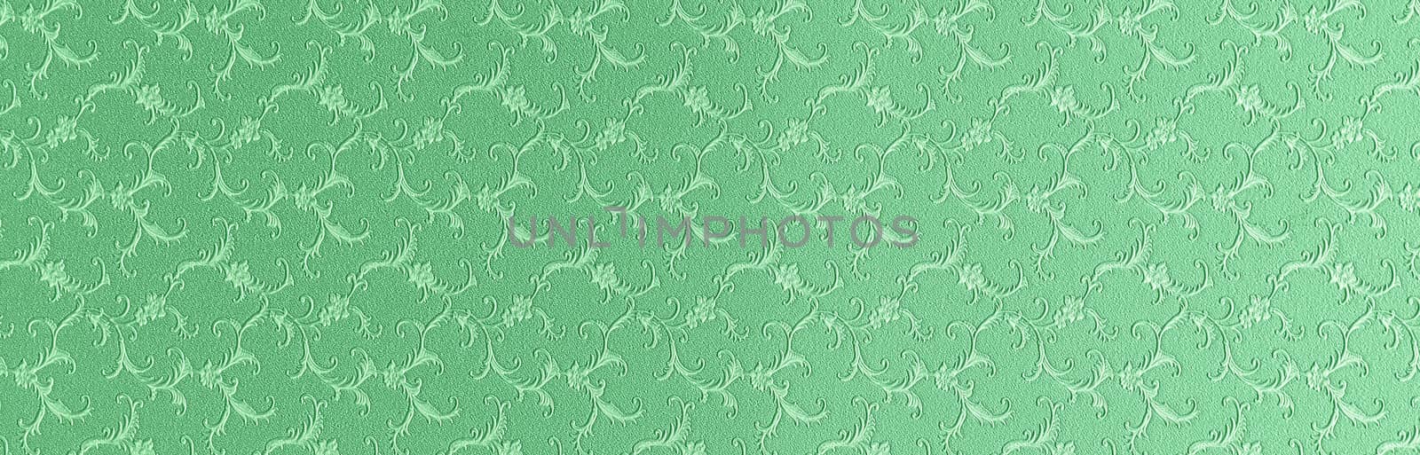 Embossed floral pattern on green paper. Textured paper with copy space. Light green, the color of fresh grass, paper surface, texture closeup.