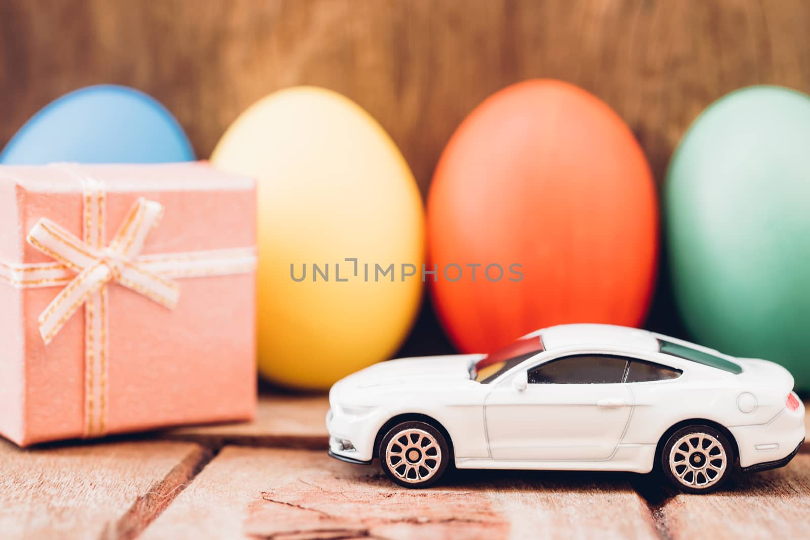 Easter egg and toy car on wooden background, happy easter day concept
