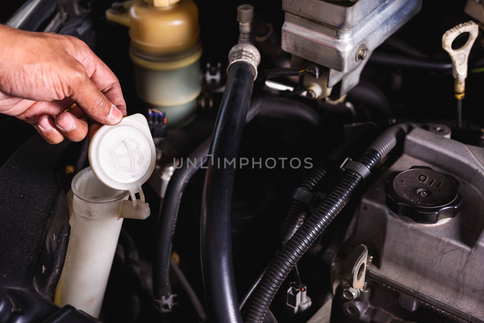 Hand of Mechanic technician service check level water on wiper lid can in garage