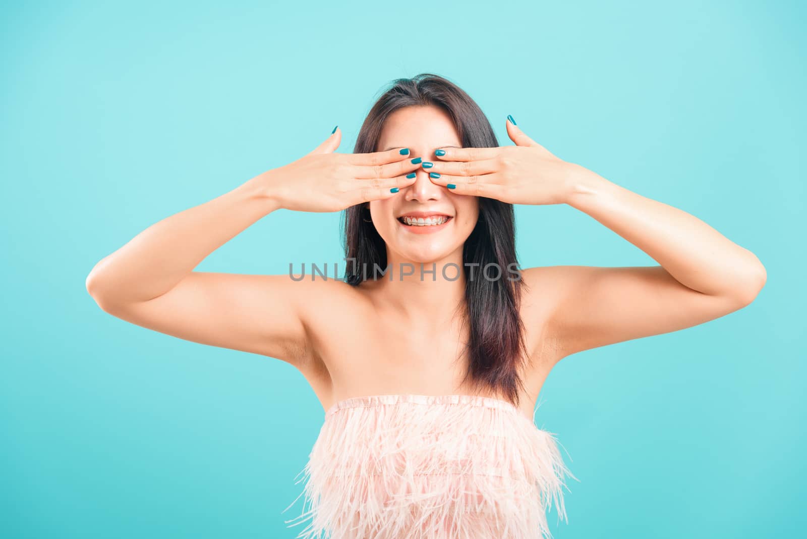 Smiling face Asian beautiful woman her covering eyes by hands on blue background,