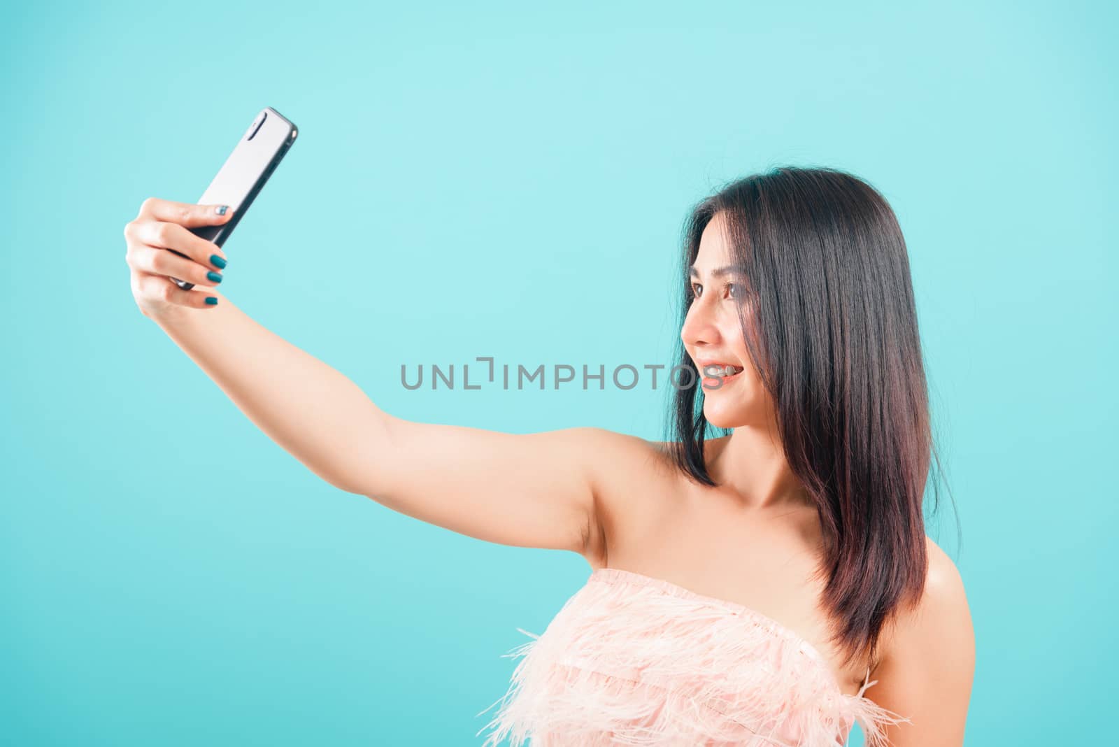 Smiling face portrait asian beautiful woman her standing making selfie photo on smartphone on blue background