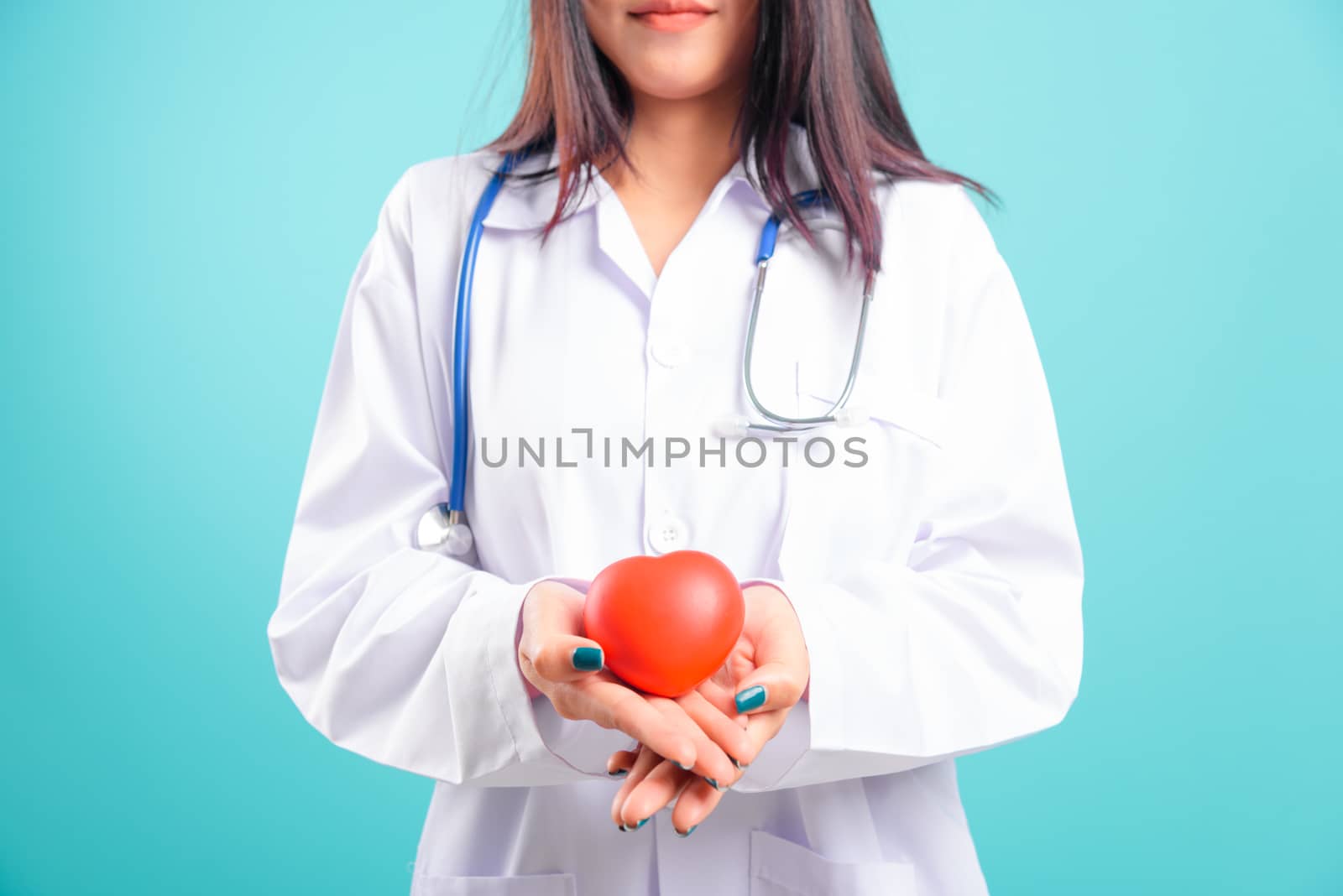 Portrait asian beautiful doctor woman smiling her standing with stethoscope holding heart on blue background, with copy space for text