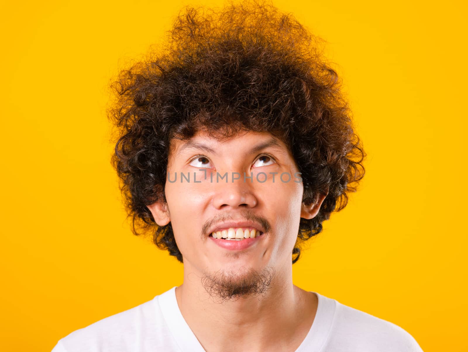 Asian handsome man with curly hair looking up see he hair isolate on yellow background with copy space for text