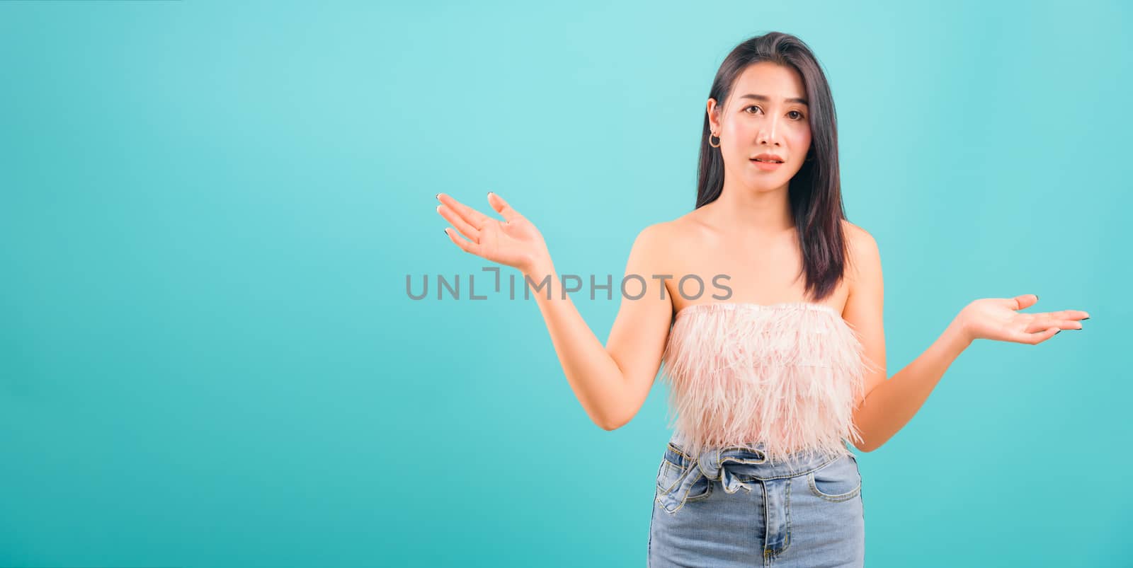 Asian beautiful woman her confused throwing hands aside on blue background, with copy space for text