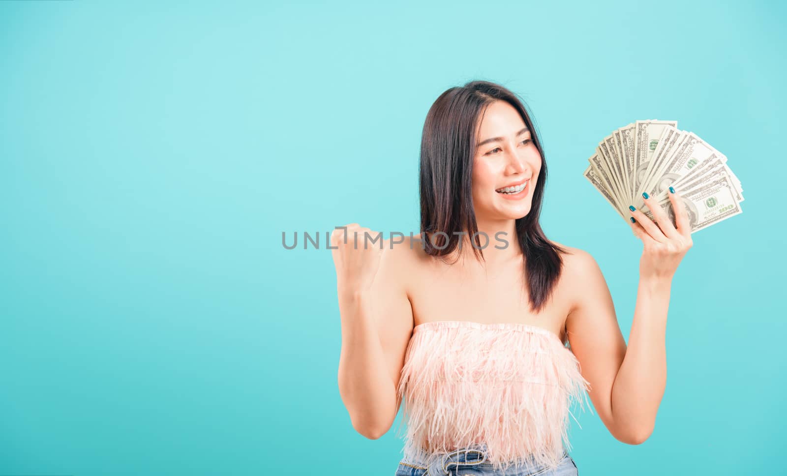Smiling face portrait asian beautiful woman cheerful her holding money on blue background, with copy space for text